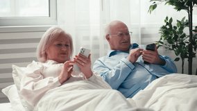 Happy senior couple browsing social networks on their phones in bed, a sign of gadget addiction - Powered by Shutterstock - Get 15% off with code: PIKWIZARD15