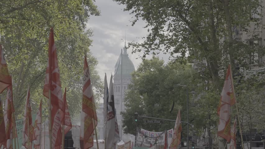 Left-wing political flags with the Argentine national congress in the background