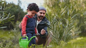 A joyful moment captures a father and his young son gardening together, teaching about nature with a green watering can outdoors. - Powered by Shutterstock - Get 15% off with code: PIKWIZARD15