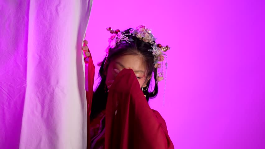 A woman in a red dress with a flowery headpiece poses for a photo. The image has a bright and cheerful mood, with the woman