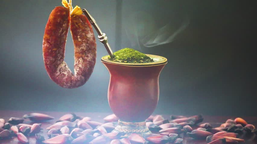 Traditional Brazilian chimarrão typical gaucho with yerba mate in a special video with dramatic lighting in a rustic environment with Araucária pine trees and smoked salami