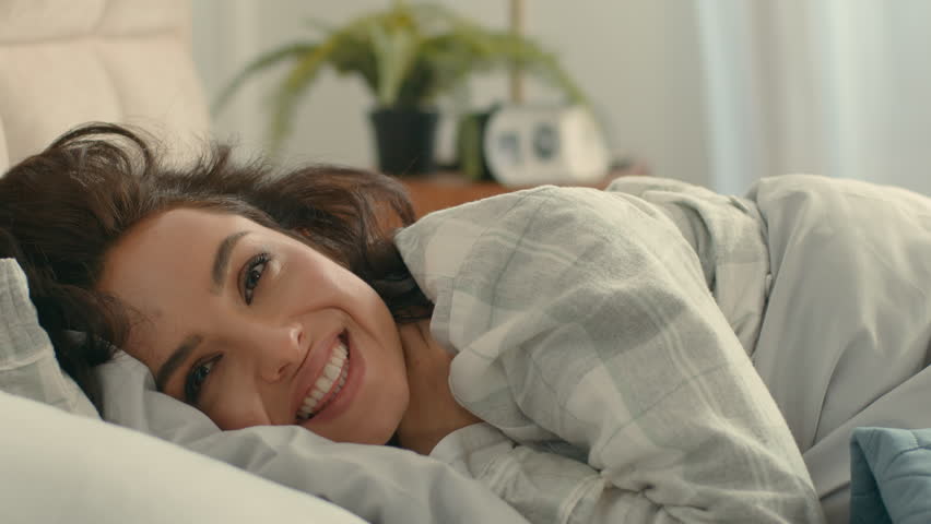 Happy Caucasian woman lying bed bedroom girl wake up female good morning smiling laugh enjoyment pleasure awake bedding wellbeing comfortable positive lazy daydream napping satisfied relaxed homeowner
