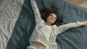 Top view Caucasian Young woman brunette fall on bed rest pleasure happiness smile laughter fun girl bedroom domestic lifestyle carefree lady enjoy positive relaxed lying soft mattress cozy comfortable - Powered by Shutterstock - Get 15% off with code: PIKWIZARD15