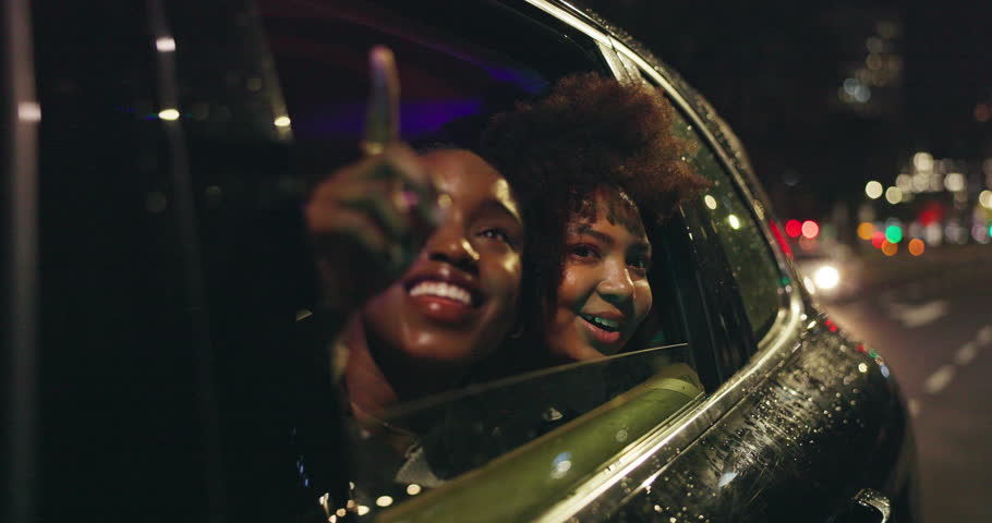 Women, friends and window of car in night for city view, travel and outdoor street excitement for new urban life. Girls, driving and pointing downtown with wind in hair for ride sightseeing and tour.