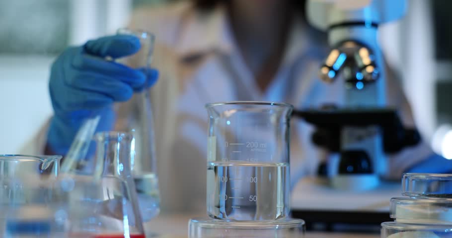 Chemical laboratory experiment pouring and mixing liquid. Water quality control and testing