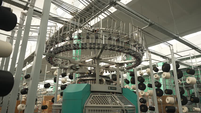 Knitting machines at textile factory. Vertical installation of circular knitting machines with spools of yarn. Concept of textile knitting technology