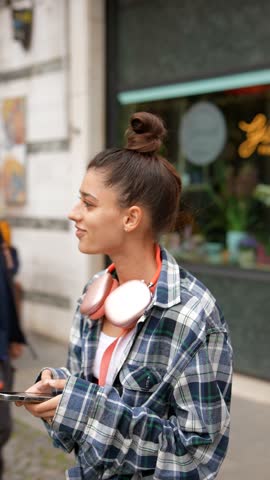 A traveler, in her youth, wanders the city streets, seeking information on her smartphone.