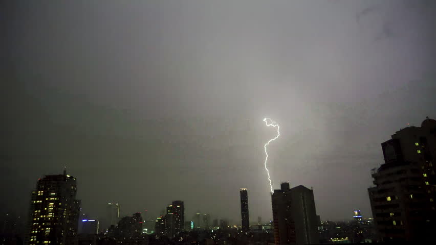 Lightning and rain in modern city center of Bangkok. Storm clouds with lightning strike bolts passing over night city of Bangkok cityscape.