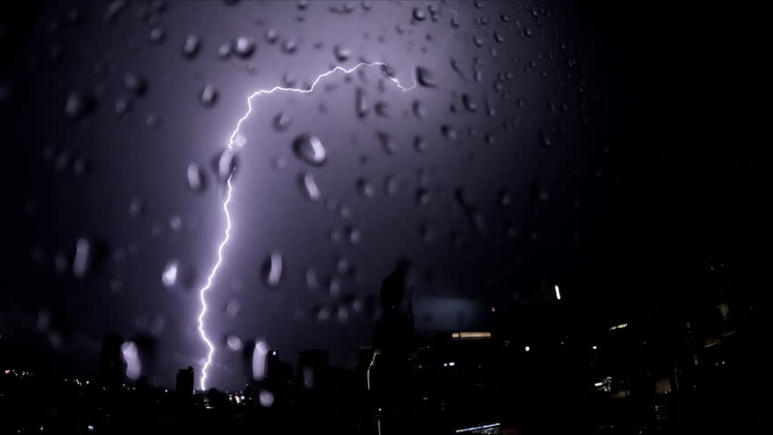 Lightning and rain in modern city center of Bangkok. Storm clouds with lightning strike bolts passing over night city of Bangkok cityscape.