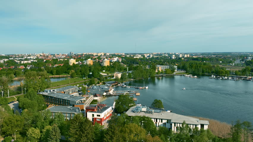 Aerial approaching shot of port with boats at River in Olsztyn Town. Green trees and residential area with houses in background, Poland.