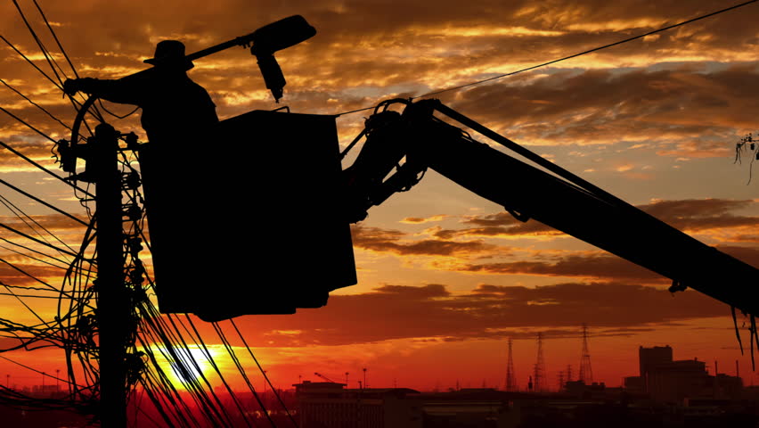 Silhouette of an electrician to repair street lighting with sunset time lapse
