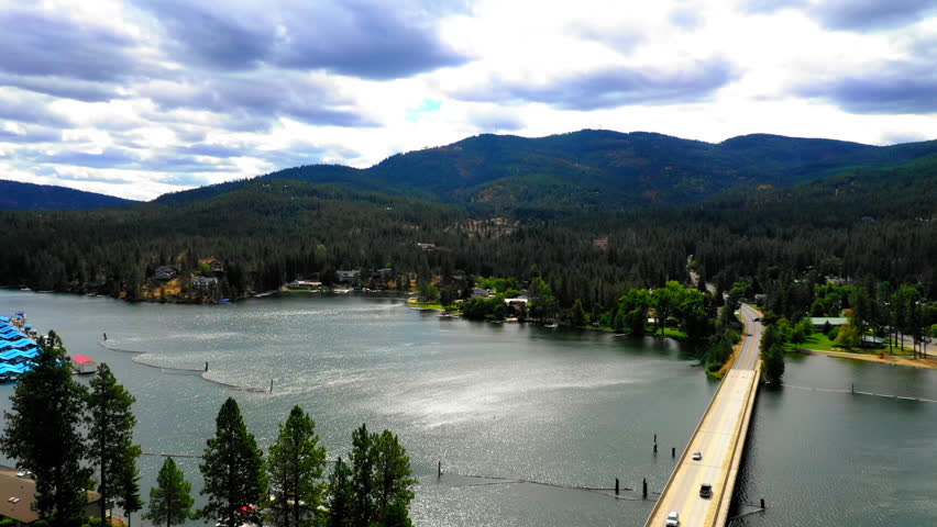 Aerial Backward Scenic Shot Of Water Tower By Bridge On River In Town Under Cloudy Sky - Coeur d