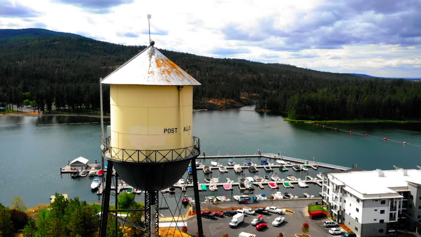 Aerial Panning Shot Of Water Storage Tower By Nautical Vessels At Harbor In River Under Cloudy Sky - Coeur d