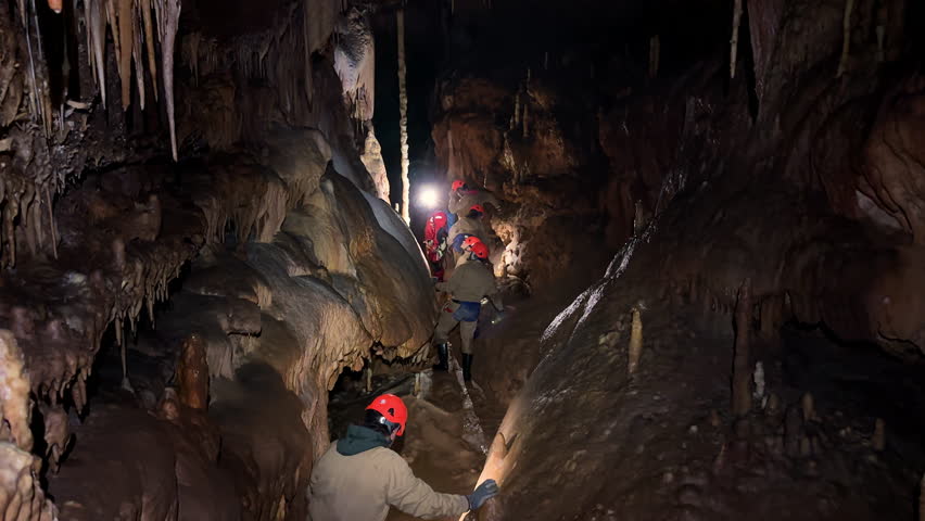 Group of unrecognizable speleologists exploring rocky cave. High quality 4k footage