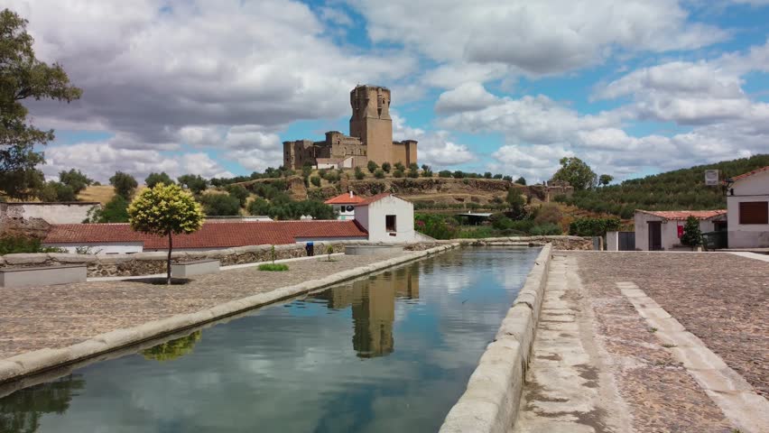 Belalcazar Castle in Cordoba, Spain on a sunny day with reflection in a calm water channel