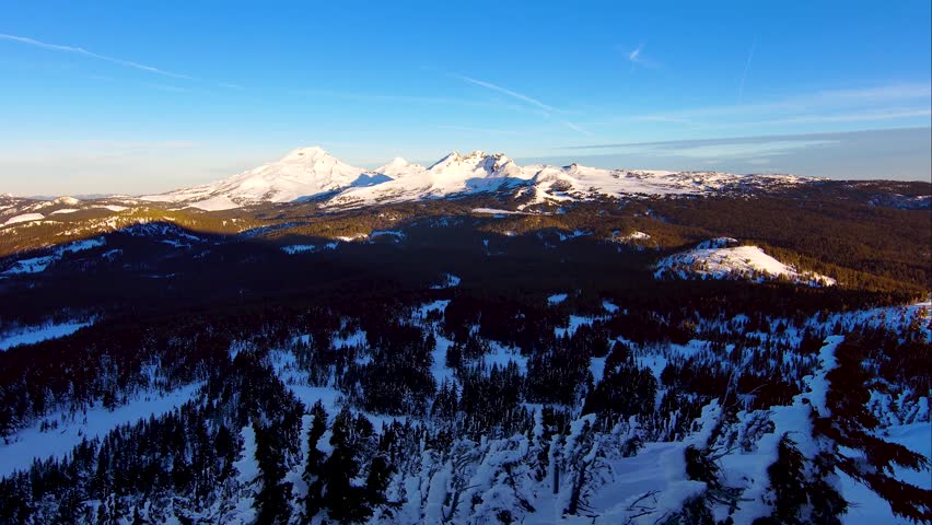 Drone captures the majestic Sisters Mountains in winter alpenglow, Central Oregon.
