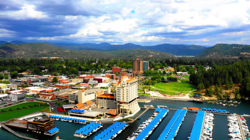 Aerial Panning Scenic View Of Hotel In Residential Green Town, Drone Flying Over Harbor On River Under Cloudy Sky - Coeur d
