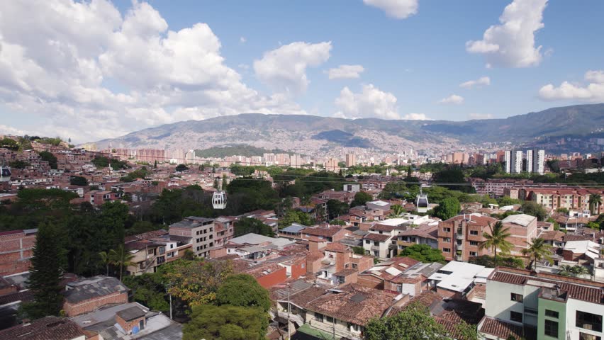 Metrocable ropeway over urban slum district in Medellin Town, Colombia. Tourist attraction in dangerous district. Aerial wide shot.