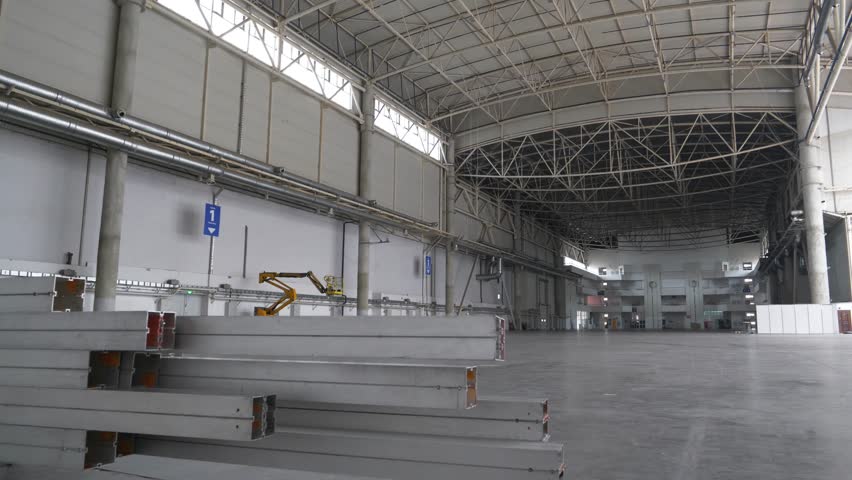 Metal structures lie in large warehouse. Large empty storehouse or huge premise for exhibitions