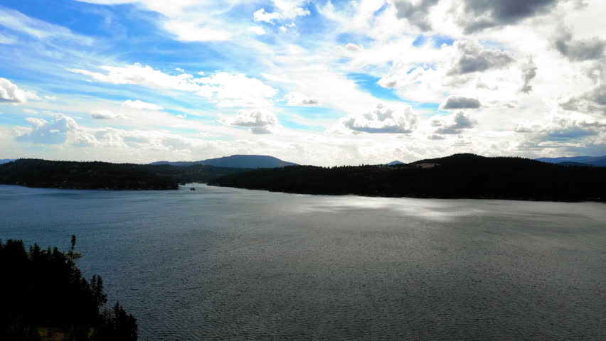 Aerial Forward Beautiful Shot Of Rippled Sea And Mountains Under Clouds In Sky - Coeur d