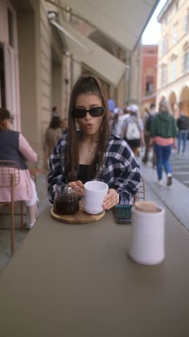 A fashionable young lady dines on a morning terrace in a European town.