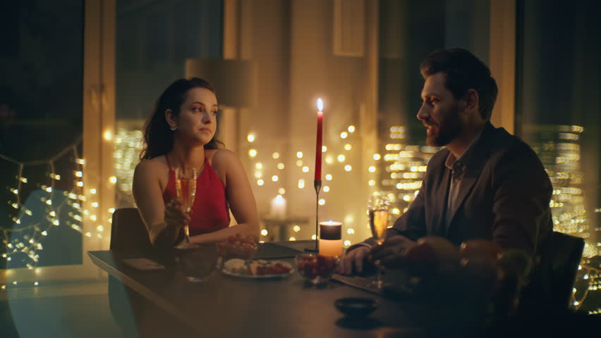 Sweet couple talking romantic home evening closeup. Smiling man woman sitting table at cozy dark interior. Loving spouses enjoying dinner with candles. Happy family anniversary celebration concept 