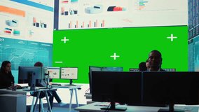 Diverse group of business specialists solve their daily tasks in control room with big greenscreen, analyzing big data numbers to ensure organizational progress. Startup management team. Camera B. - Powered by Shutterstock - Get 15% off with code: PIKWIZARD15