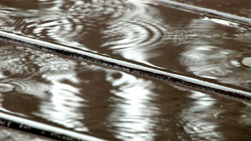 Raindrops falling onto a deck.
