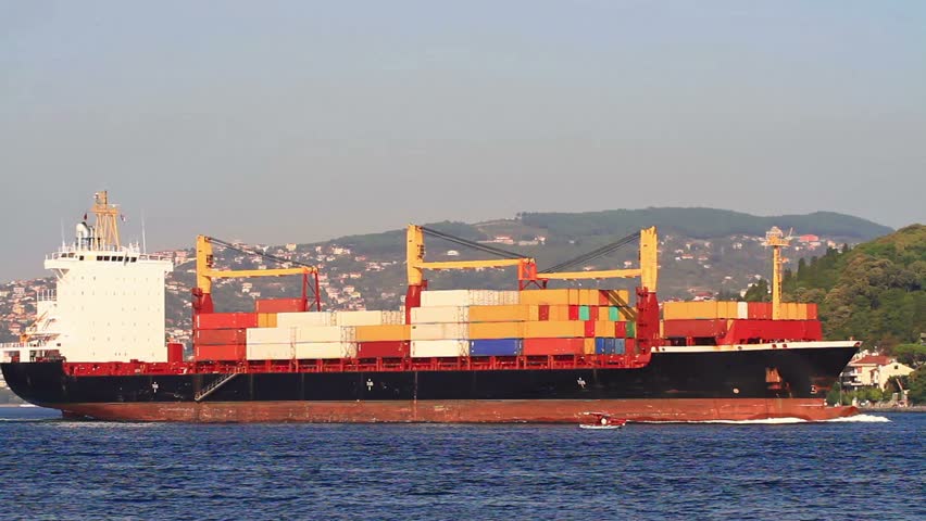 A large container ship full of cargo sailing along the shore