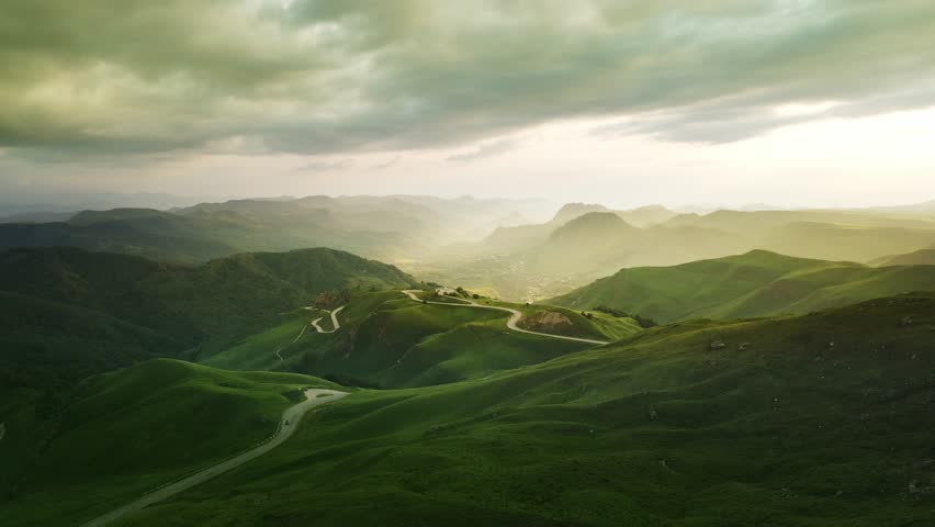 View of the green mountains and hills at sunset. Road in the mountains. Aerial view. Beautiful summer landscape. Gumbashi Pass in North Caucasus, Russia. 
