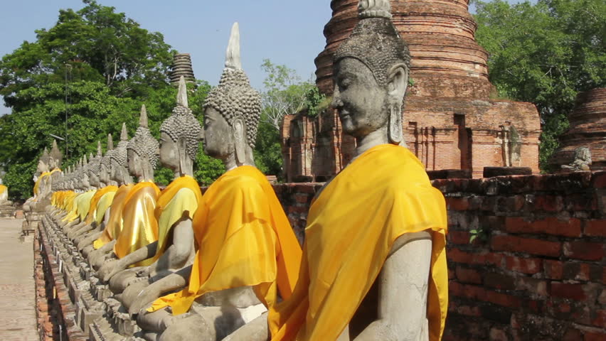 Row of sitting Buddha statues dolly shot Temple in Thailand