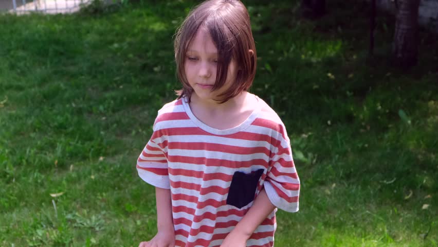 A beautiful brunette girl 8-10 years old, or a teenager dancing and having fun on the street or in the backyard of her house under the sun, the concept of a happy childhood and future