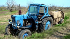 Old blue agricultural tractor stands in orchard and prepares to spray pesticides on flowering trees. Spraying flowering cherry orchard to protect against disease and insects with tractor and - Powered by Shutterstock - Get 15% off with code: PIKWIZARD15