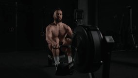 Man exercising on rowing machine, wearing only shorts, bare chest. Routine workout for physical and mental health. - Powered by Shutterstock - Get 15% off with code: PIKWIZARD15