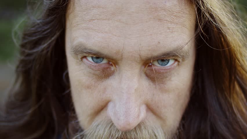 Portrait of a man with a mustache and beard and long hair in a medieval knight costume who stubbornly looks forward from under his forehead