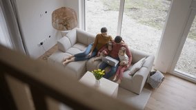 Top view of family with small daughter sitting on sofa in their new home. Young family buying a first house, big milestone and home ownership concept. - Powered by Shutterstock - Get 15% off with code: PIKWIZARD15
