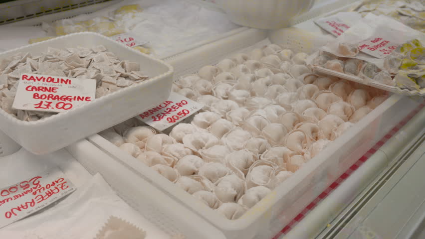 At the oriental market in Genoa, Italy, a stall selling local specialties of fresh stuffed pasta: the gaze passes over the trays with different formats with name and price tags.