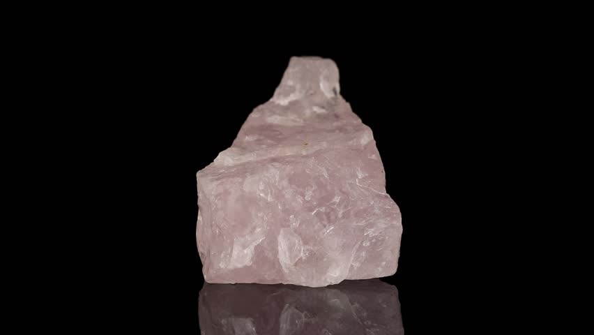 Polished mineral stone rose quartz rotates in a circle on a black background close up