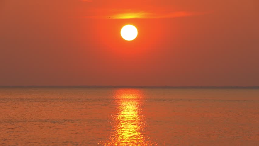 Epic cinematic sunset dawn in the ocean time lapse. Big sunset over sea. Close up telephoto lens waterscape orange colour sun time lapse. Red sun light reflection and sparkles on water waves.