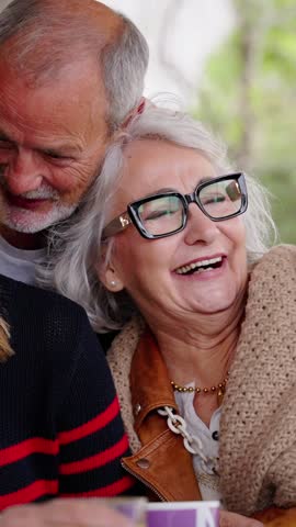 Vertical. Group joyful seniors Caucasian people posing for picture laughing together sitting indoor. Older cheerful friends with gray hair embracing. Lifestyle happy matures having fun in nursing home