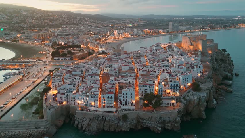 Aerial view of Peniscola beach and castle at twilight, Peniscola is a popular coastal town on Costa del Azahar, Province of Valencia, Spain. Drone night shot of medieval Spanish town