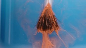 The orange liquid paint stream spreads from the artist's brush into the blue water, creating interesting patterns. Slow-motion macro. - Powered by Shutterstock - Get 15% off with code: PIKWIZARD15