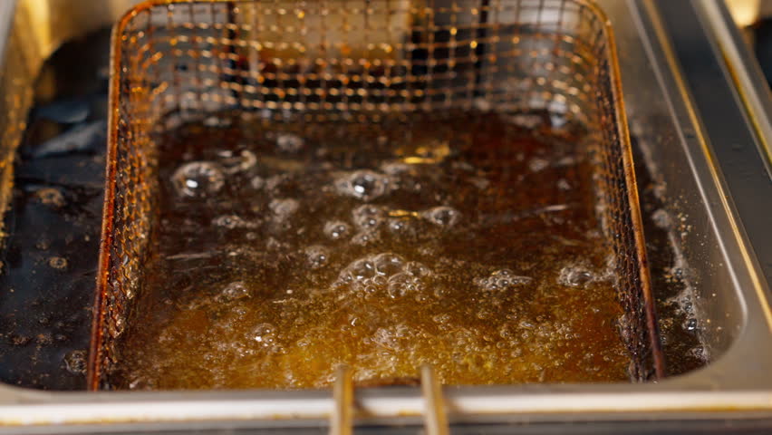 close-up in professional kitchen frying French fries in oil in a deep fryer