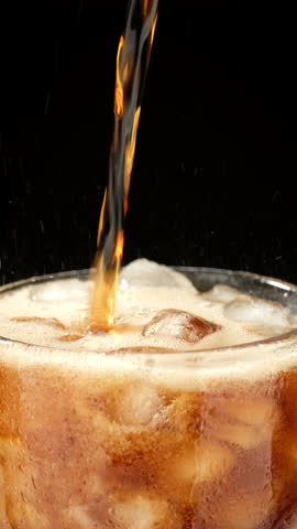 Refreshing drink in glass with ice, black background