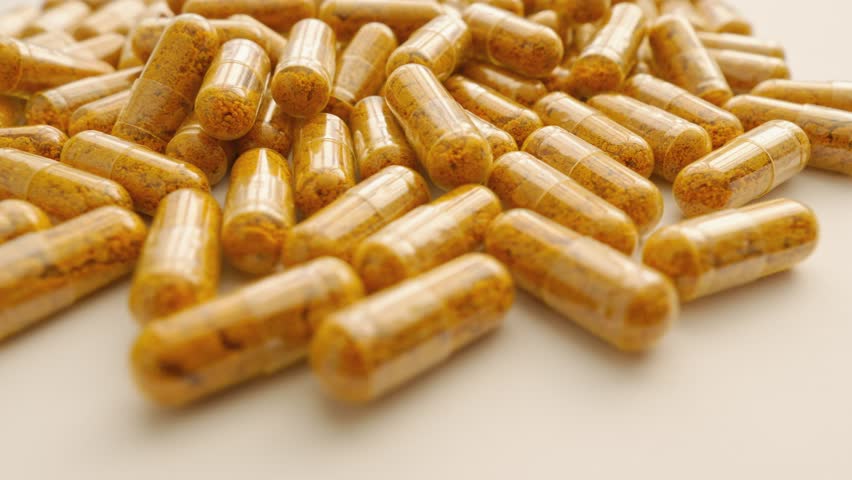 Turmeric capsules spin on a movable platform. Flying around the camera around the medicinal capsules. Medicines and dietary supplements in the role of turmeric and curcumin.