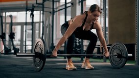 in the gym coach girl in a black top is standing doing exercises with a barbell and weights - Powered by Shutterstock - Get 15% off with code: PIKWIZARD15