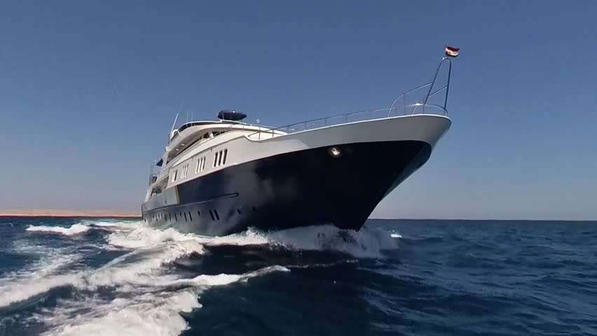 Bow of a large luxury private motor yacht under way sailing on tropical sea with bow wave