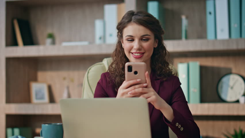 Happy entrepreneur messaging online using mobile phone at workplace closeup. Beautiful girl young director texting making order in smartphone. Joyful relaxed businesswoman check sms resting at buro.