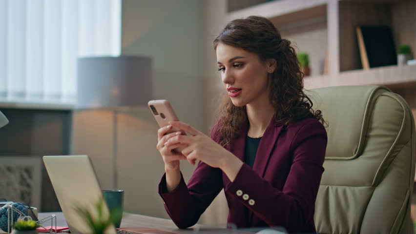Happy entrepreneur messaging online using mobile phone at workplace closeup. Beautiful girl young director texting making order in smartphone. Joyful relaxed businesswoman check sms resting at buro.
