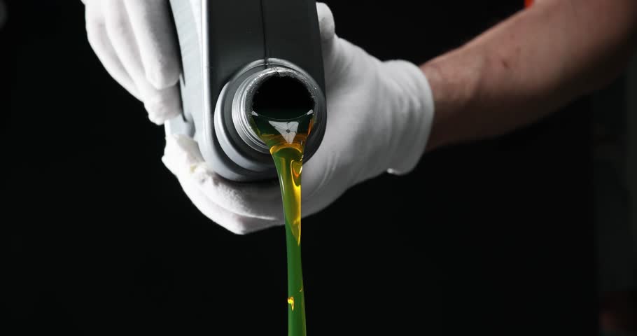 Jar filled with automotive engine oil in hands of craftsman. Car mechanic pouring engine oil